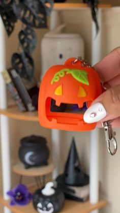 a hand holding an orange plastic keychain with a cartoon pumpkin on it