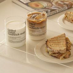 two plates with sandwiches on them next to a glass of milk and a book that reads grilled cheese sandwich recipe