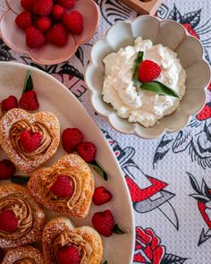 strawberries and pastries are arranged on a table with other desserts in bowls