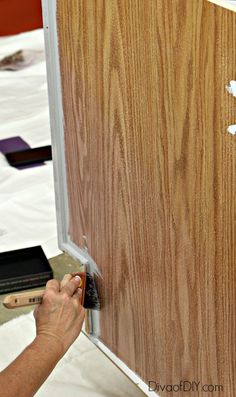 a person is working on a wood paneled door with white paint and some scissors