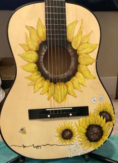 an acoustic guitar with sunflowers painted on it