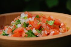 a wooden bowl filled with chopped tomatoes and cilantro