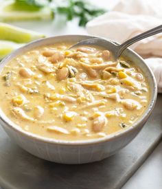 a white bowl filled with soup on top of a metal tray next to some vegetables