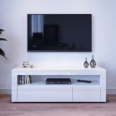 a flat screen tv mounted to the side of a white entertainment center