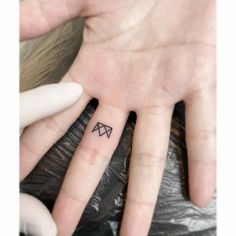 a person's left hand with a small tattoo on the middle finger and an arrow