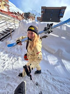 a woman holding skis on top of snow covered ground