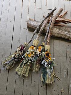 three bundles of dried flowers sitting on top of a wooden floor next to sticks and twigs