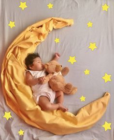 a baby laying on the moon with a teddy bear in it's lap and yellow stars around him