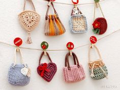 small crocheted purses are hanging on a clothes line with buttons and pins