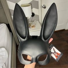 a person wearing a black bunny mask and holding up a card in front of their face