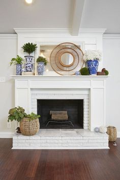 a living room with a fire place and potted plants on top of the fireplace