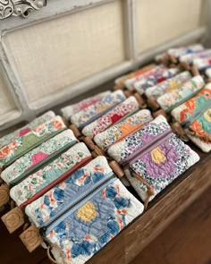 many small wallets are lined up on a table in front of an old window