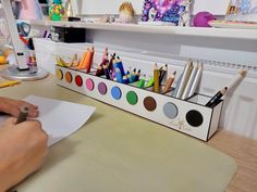 a person sitting at a desk with some colored pencils and markers in front of them