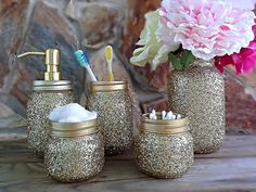 three gold glittered jars with toothbrushes and toothpaste in them