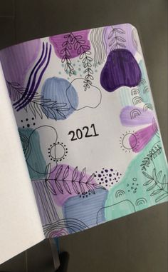 an open notebook with the year 2021 written on it and colorful flowers in the background