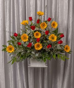 a white vase filled with yellow and red flowers