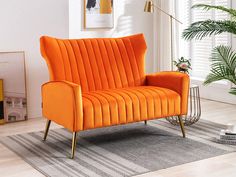 an orange chair sitting on top of a rug in a living room next to a potted plant