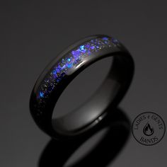 a wedding ring with blue fire opal inlaying the center, on a dark background