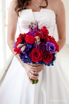 a bride holding a bouquet of red and purple flowers