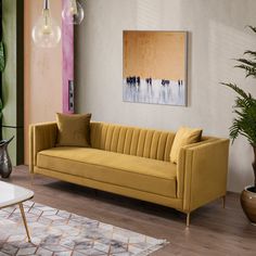 a living room with yellow couches and potted plants on the floor in front of it