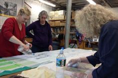 three women are working on crafts in a workshop with water bottles and papers laid out on the table