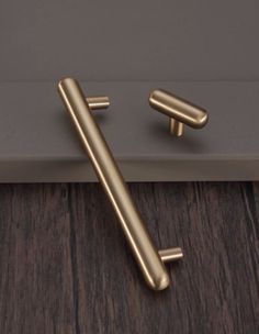 an image of two handles on a door handle in gold color with dark wood flooring