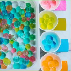 three bowls filled with different colored candies on top of a white table next to each other