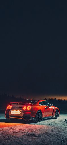 a red sports car parked in the snow at night