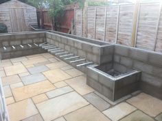 a stone patio with steps leading up to the back wall and an outdoor fire pit