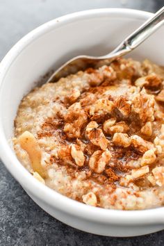 a white bowl filled with oatmeal topped with walnuts and a spoon