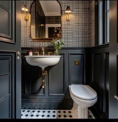 a bathroom with black and white checkered wallpaper, gold fixtures and a pedestal sink