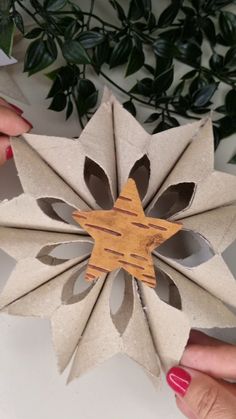 two hands holding up an origami flower made out of brown and white paper