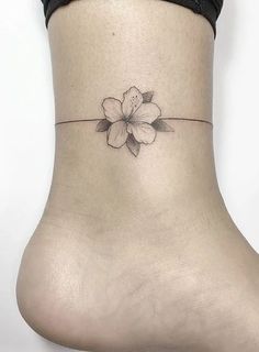 a woman's foot with a small flower tattoo on the side of her ankle