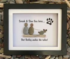 two pebbles are sitting on a branch with a paw print in the frame