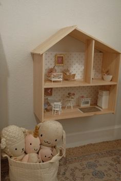 there are stuffed animals in a basket on the floor next to a shelf with dolls