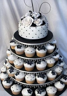 a three tiered wedding cake with cupcakes on the bottom and black and white frosting