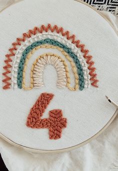 an embroidery project with the number four in front of it and a cross stitched rainbow