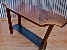 a wooden table sitting on top of a hard wood floor next to a metal wall