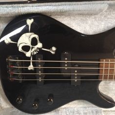 a black guitar with a skull and crossbones on it's body in a case