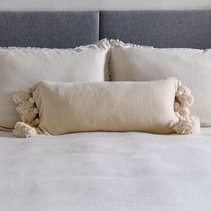 a bed with white linens and two pom - poms on the pillows