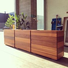 a large wooden planter sitting on top of a hard wood floor next to a window