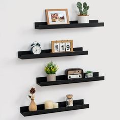 two black floating shelves with pictures and other items on them, along with a clock