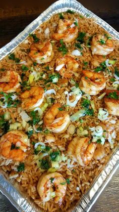 a tray filled with rice and shrimp on top of a wooden table