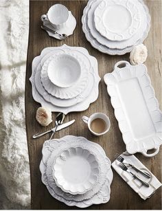 white plates and silverware are laid out on a wooden table with furnishing