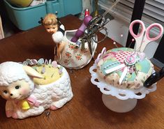 three little figurines are sitting on a table with scissors and other items in them