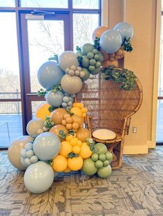 balloons and fruit are arranged in the shape of a tower on top of a chair