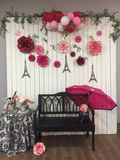 a black bench with pink and red flowers on it next to a wall decorated with balloons