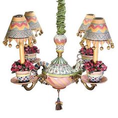 a chandelier with three lamps on top of it and flowers in the bottom