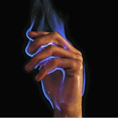 a person's hand holding something with blue light coming out of the middle of it