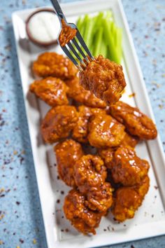 chicken wings with sauce and celery on a white plate, ready to be eaten